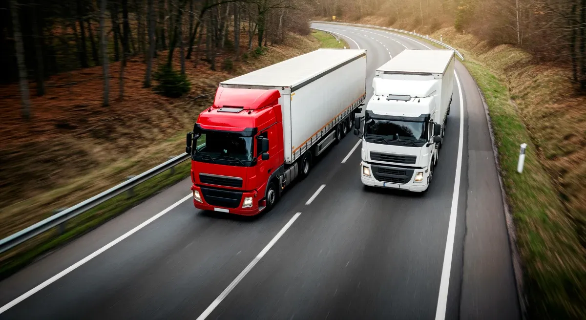 Fleet of freight trucks on a highway at dusk